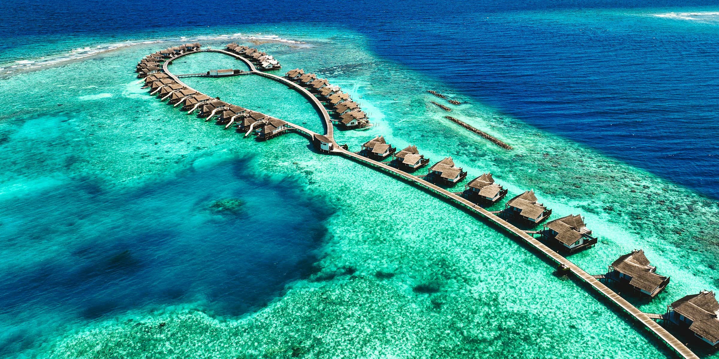 Luftaufnahme eines Malediven-Resorts mit Wasservillen